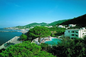 Un resort costero con piscina, playa y vistas a la colina.