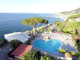 Zona de piscina con sillones de descanso y vista al mar.