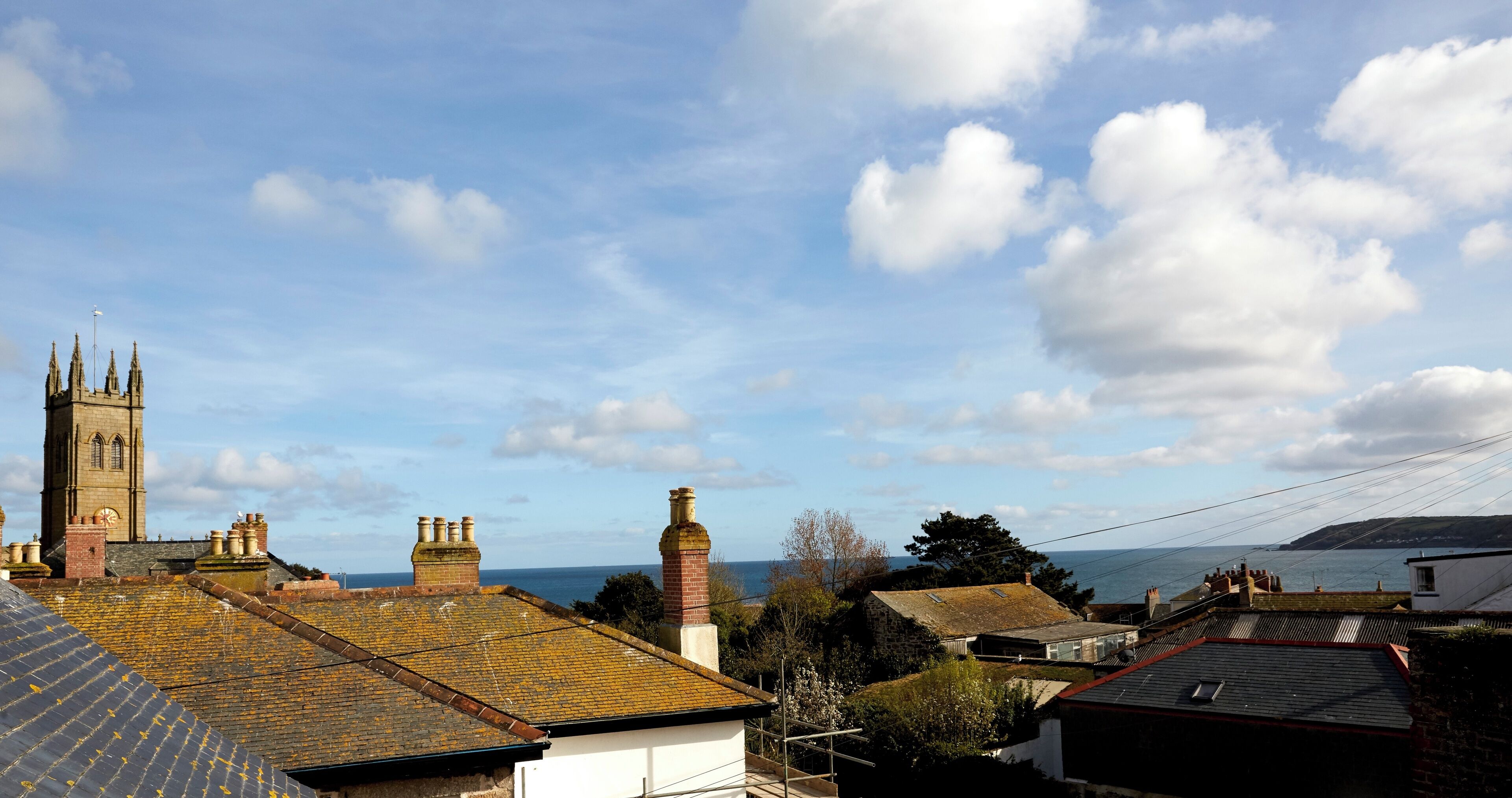 A coastal town with a prominent church tower, residential buildings, and a view of the sea.
