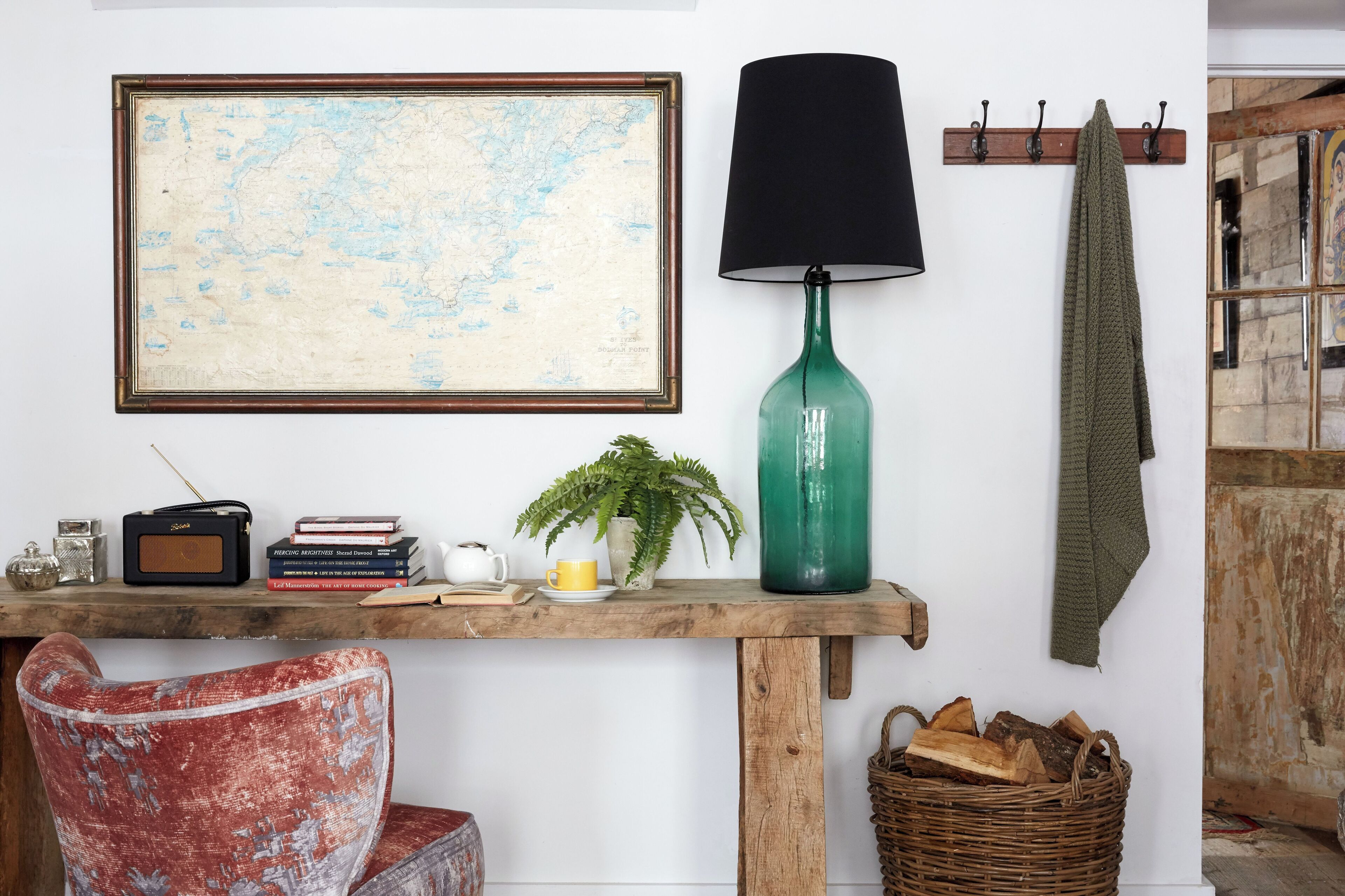 Un intérieur rustique avec une carte, une radio, des livres, une lampe et une plante sur une table en bois.