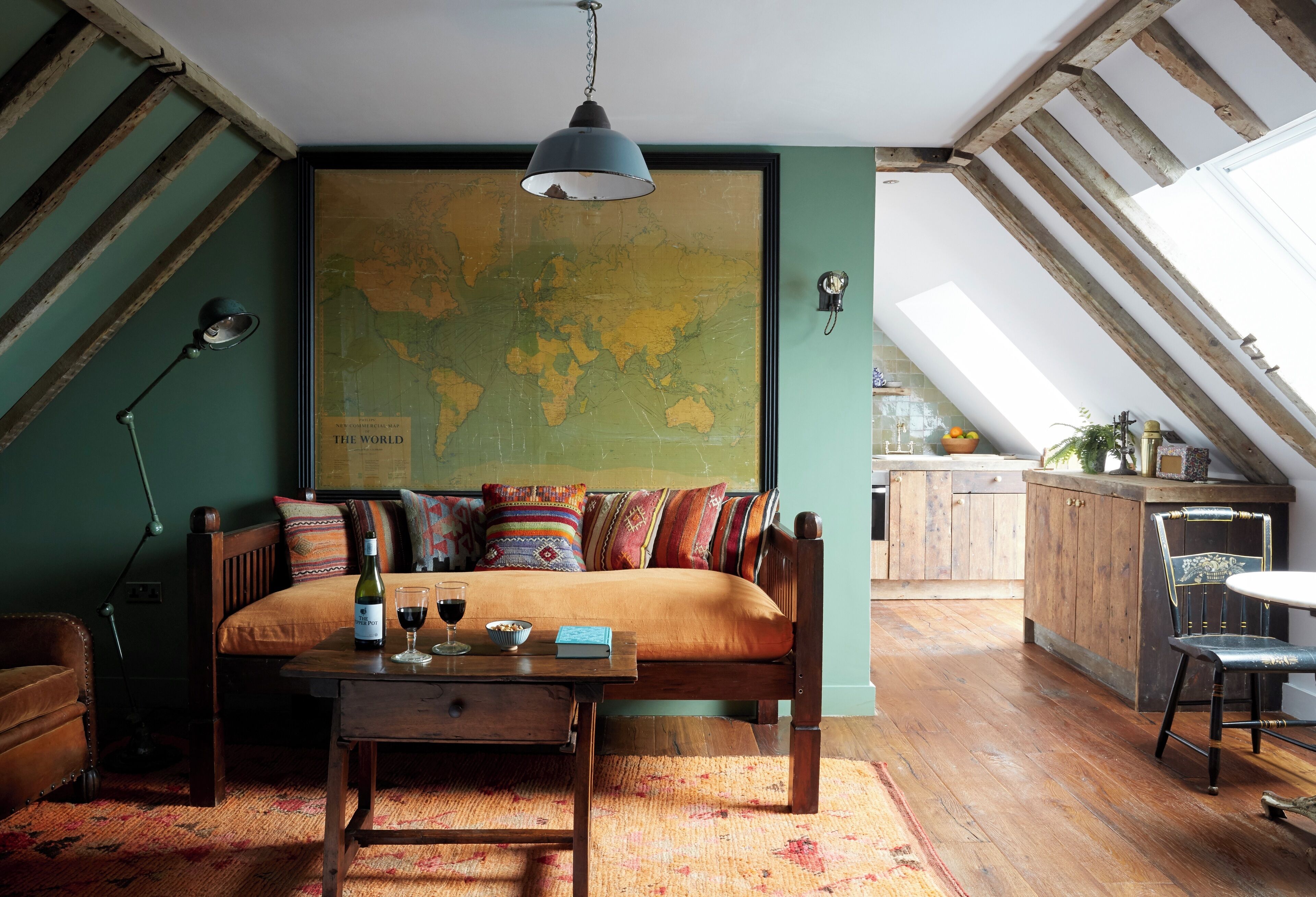 Un loft acogedor con un gran mapa del mundo en la pared, un sofá de madera, una mesa de comedor y una zona de cocina con armarios de madera.