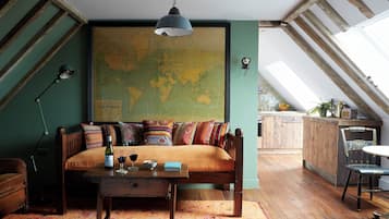 Un loft acogedor con un gran mapa del mundo en la pared, un sofá de madera, una mesa de comedor y una zona de cocina con armarios de madera.