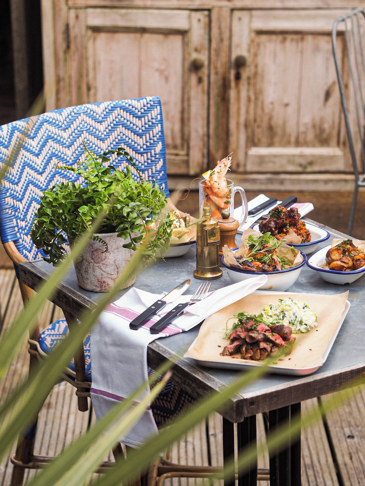 Une table à manger dressée avec différents plats, une carafe et un salier et un poivrier.
