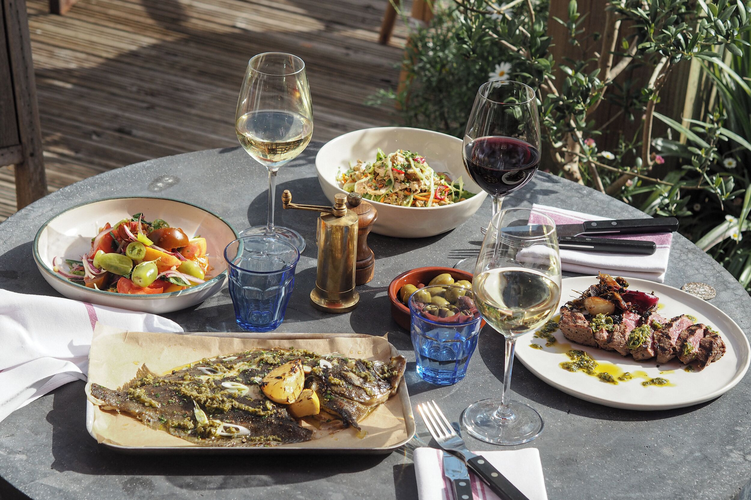 A table set with various dishes, glasses of wine, and a knife and fork.