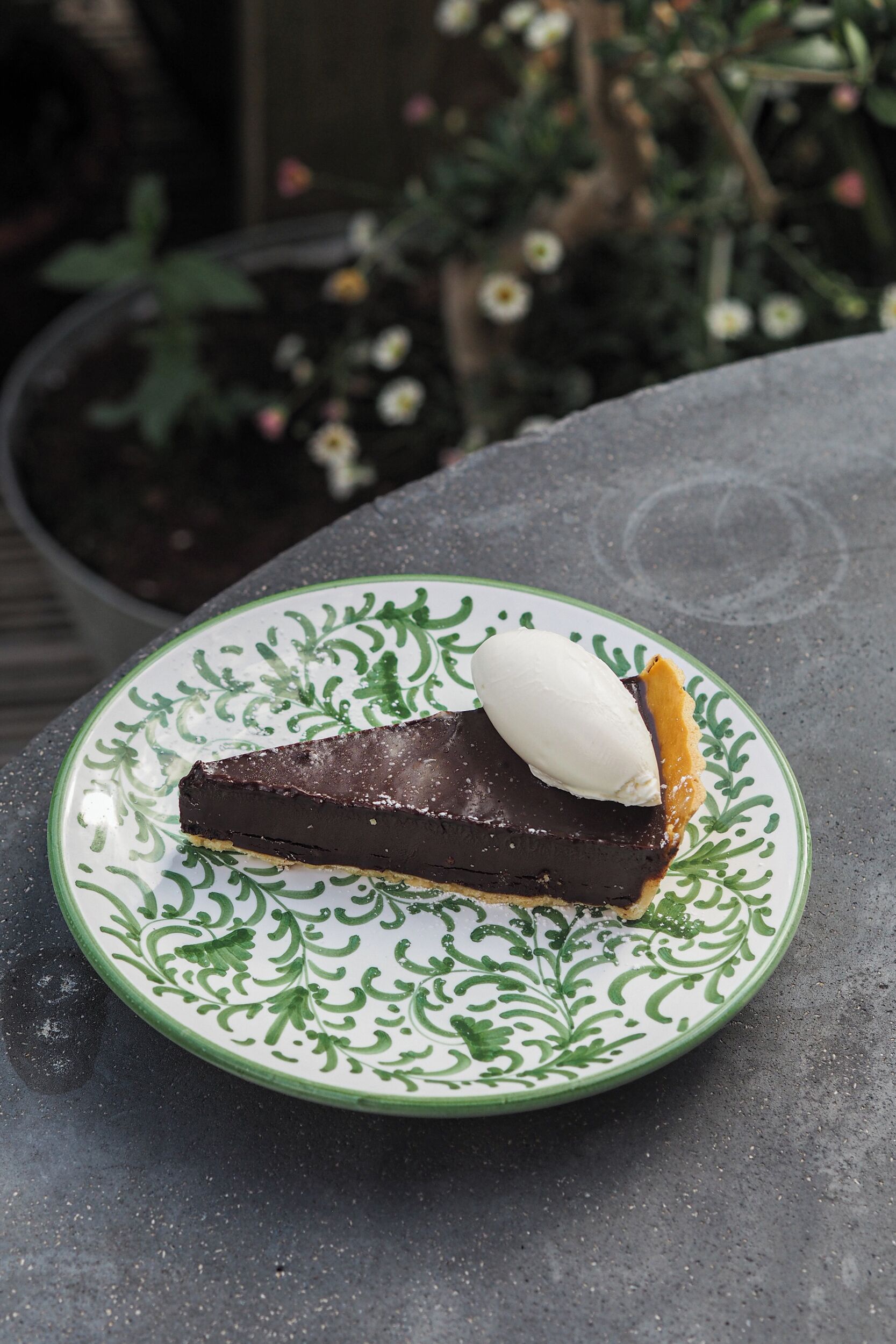 Una porción de tarta de chocolate con una bola de helado de vainilla sobre un plato decorativo.