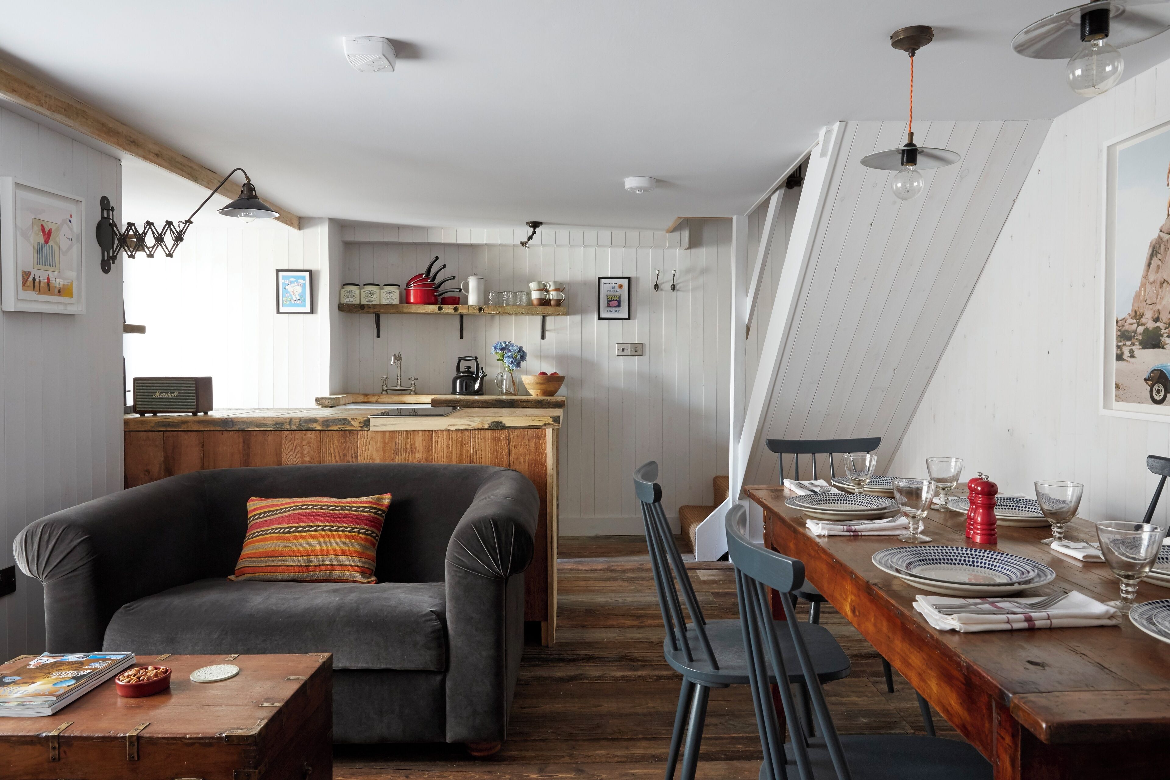 A modern kitchen with wooden cabinets, a dining table set for four, and a cozy seating area with a sofa and chairs.