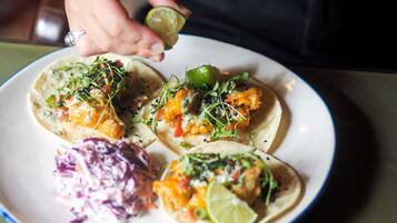 A plate of tacos with lime wedges and a side of coleslaw, accompanied by a beer mug.