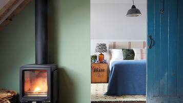 Una habitación acogedora con una estufa de leña, una cama con manta azul y una puerta azul.