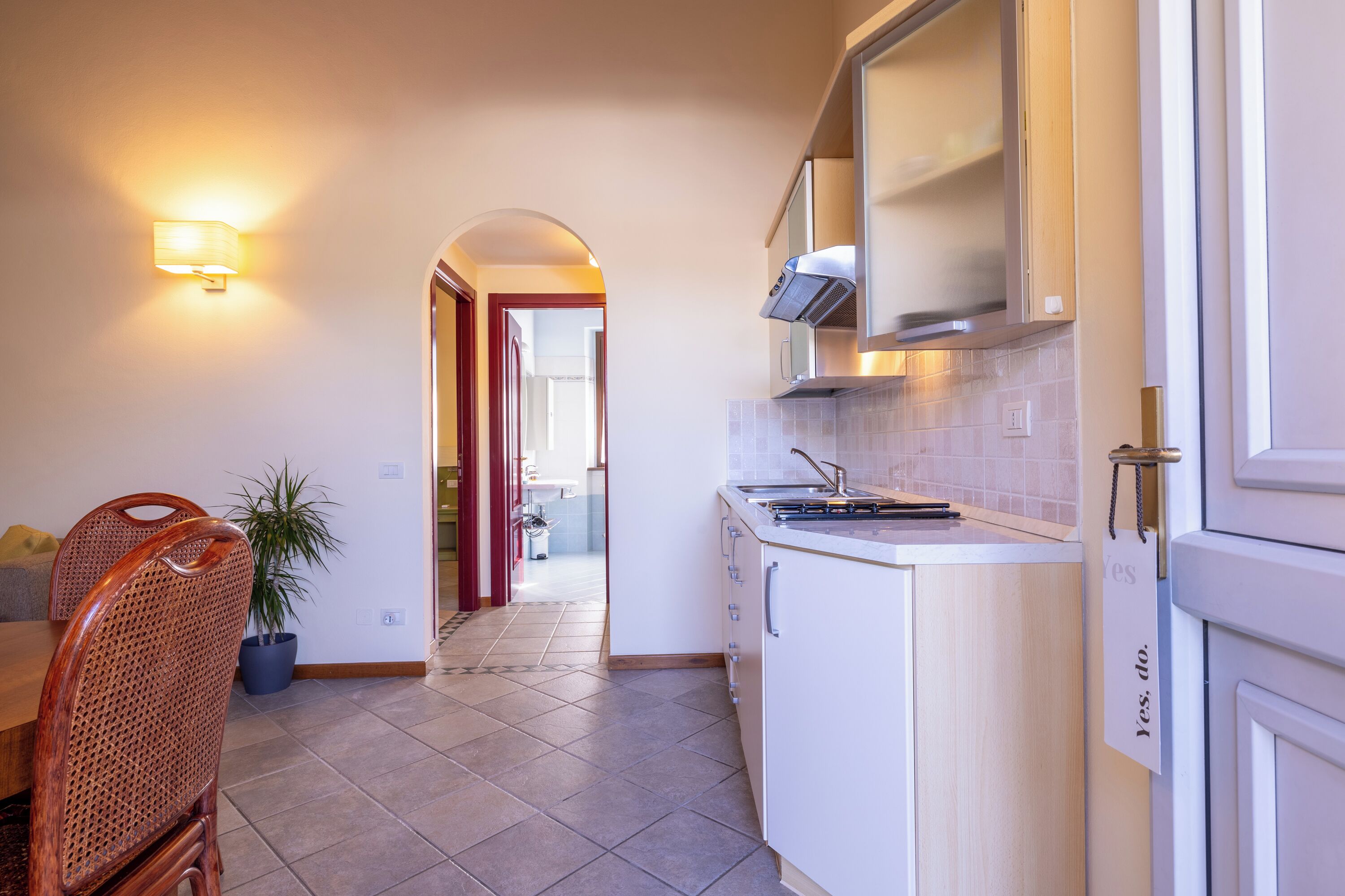 Una cucina moderna con mobili bianchi, un piano cottura integrato e un lampadario.