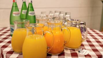 Ein Tisch mit mehreren Gläsern Orangensaft und grünen Limoflaschen.