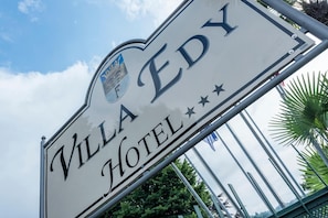 A sign for Villa Eddy Hotel with a clear view of the hotel's name and a decorative emblem. - Hotel Villa Edy (Tremezzina)