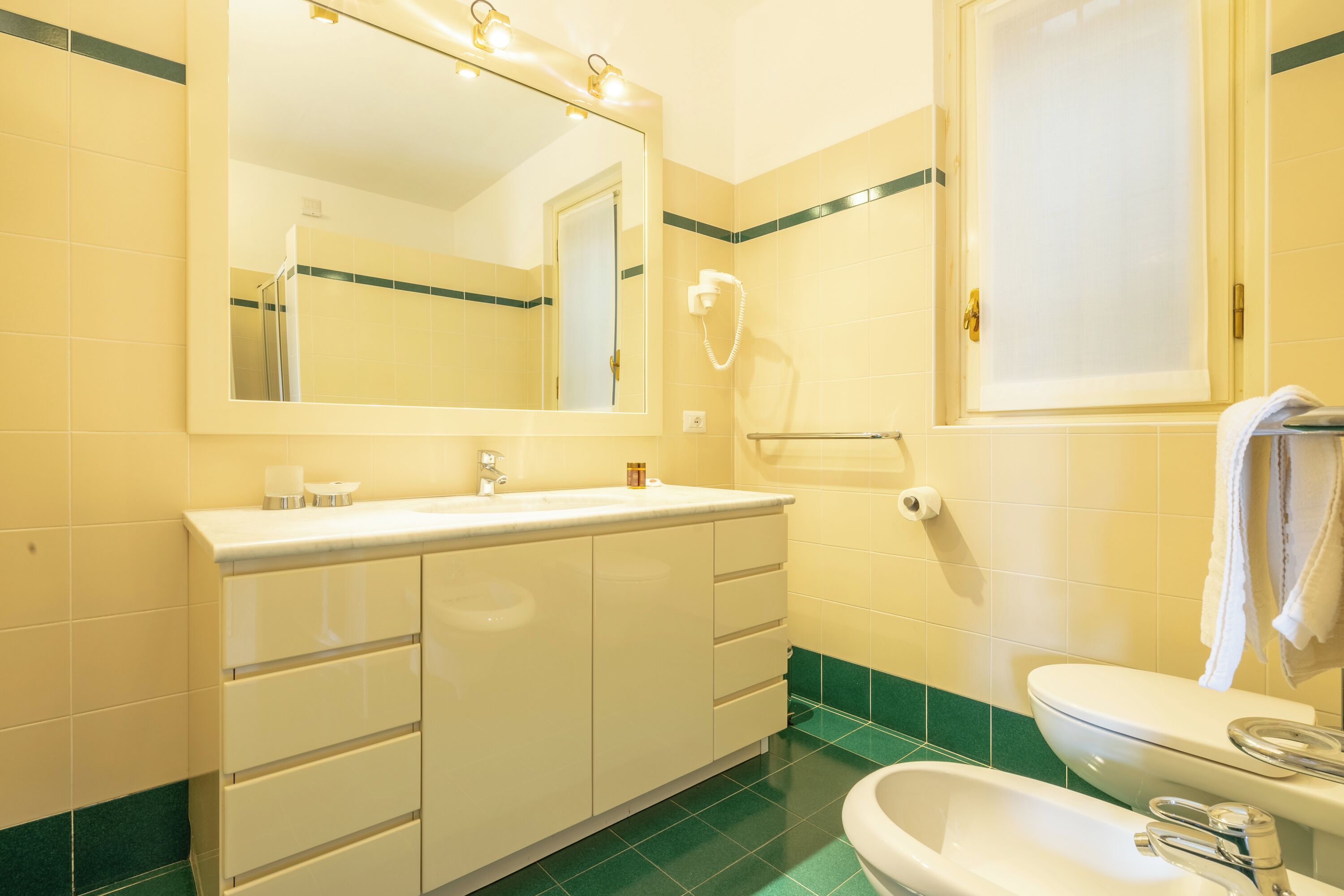A bathroom with a white sink, mirror, and toilet.