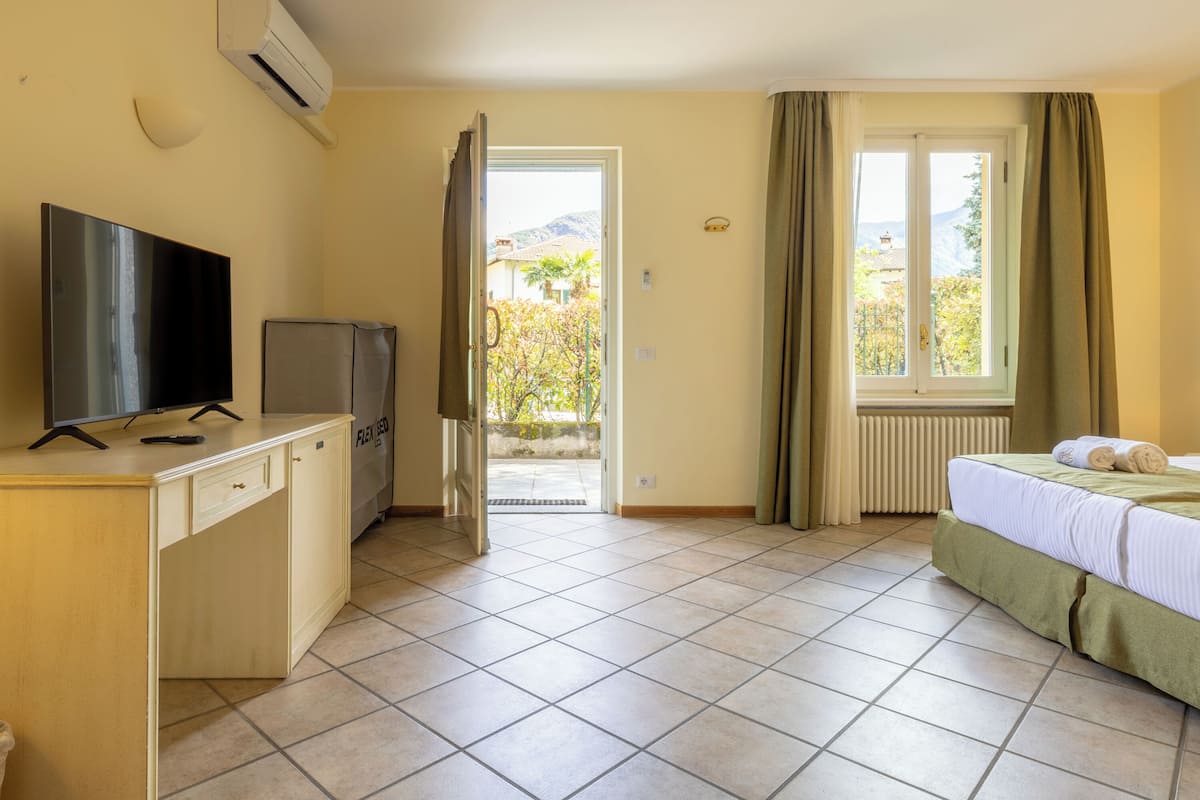 A hotel room with a bed, a TV, a desk, and a window with curtains.