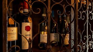 Várias garrafas de vinho em uma estante de metal, com rótulos que indicam diferentes marcas e anos.