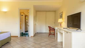 A hotel room with a bed, a desk, a chair, a TV, and a door leading to a bathroom.
