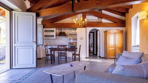 A spacious living area with a wooden ceiling, a dining table, and a sofa. - Hotel Villa Edy (Tremezzina)