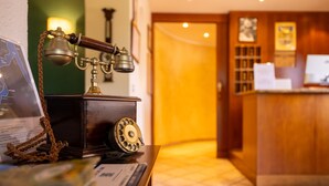 A vintage telephone on a wooden desk with a map and a framed certificate. - Hotel Villa Edy (Tremezzina)