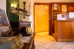 Un teléfono antiguo sobre un escritorio de madera con un mapa y un certificado enmarcado.