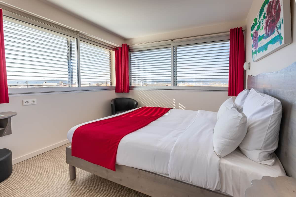 Una habitación de hotel con una cama, un escritorio y una silla.