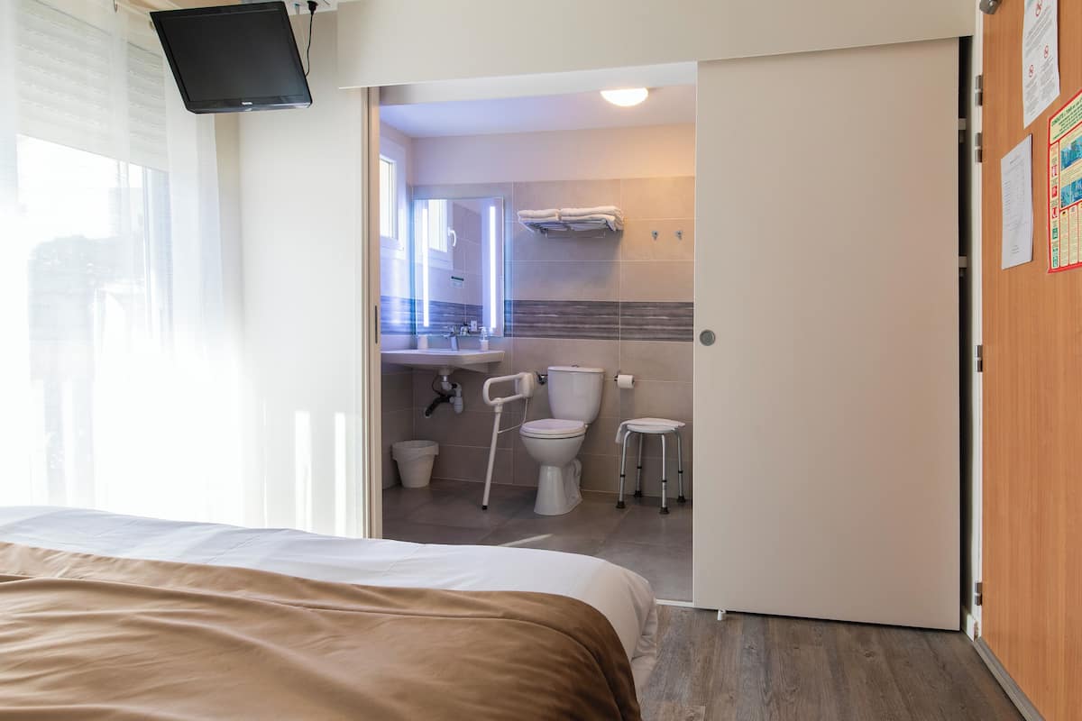 Una habitación de hotel con una cama, un baño con inodoro, lavamanos y ducha.