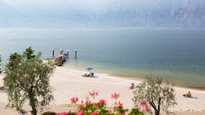 A beach with a clear view of the lake and mountains in the background. - San Remo (Malcesine)