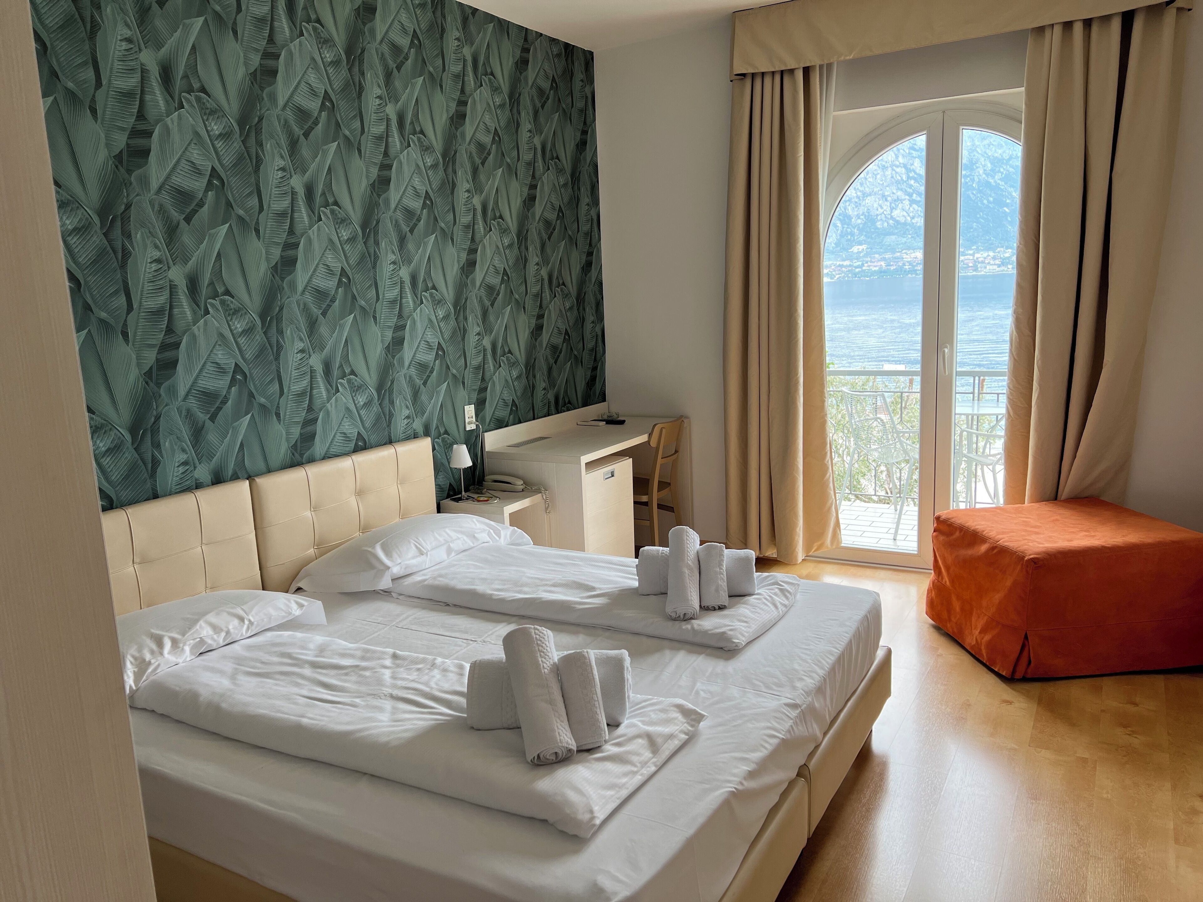 Ein Hotelzimmer mit zwei Betten, einem Schreibtisch und Meerblick.