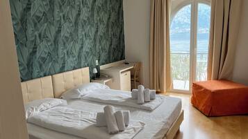 Ein Hotelzimmer mit zwei Betten, einem Schreibtisch und Meerblick.