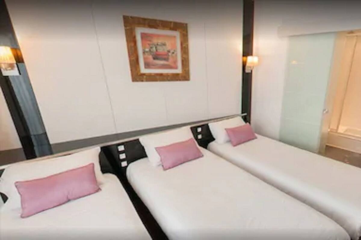 Een hotelkamer met twee enkele bedden, een douchegedeelte en een ingelijst schilderij aan de muur.