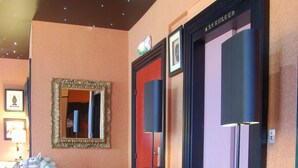 Un hall d’hôtel avec un plancher en bois, une sculpture équestre décorative, un miroir et une lampe posée sur un piédestal.