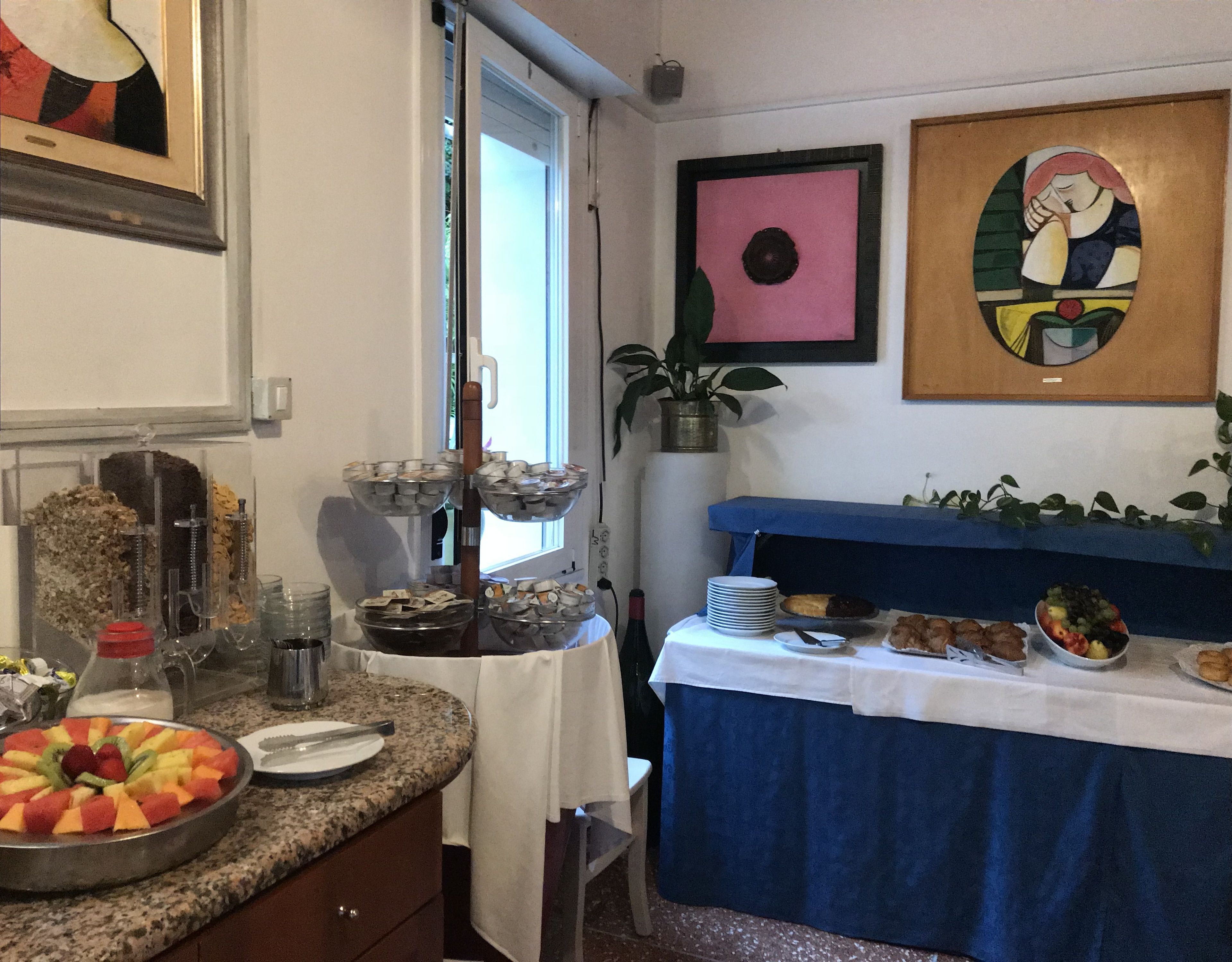 A kitchen with a fruit platter, a coffee station, and a buffet table with various dishes.
