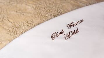 A pillow with the text "Paris France Hotel" embroidered on it.