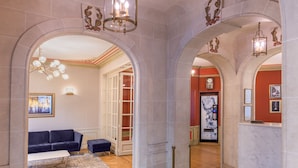 A lobby with a blue sofa, a white coffee table, and a patterned rug. There are two chandeliers and a clock on the wall. - Paris France (Paris)