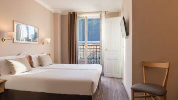 Ein Hotelzimmer mit einem großen Bett, einem Sessel, einem an der Wand befestigten Fernseher und einem Balkon mit Aussicht.