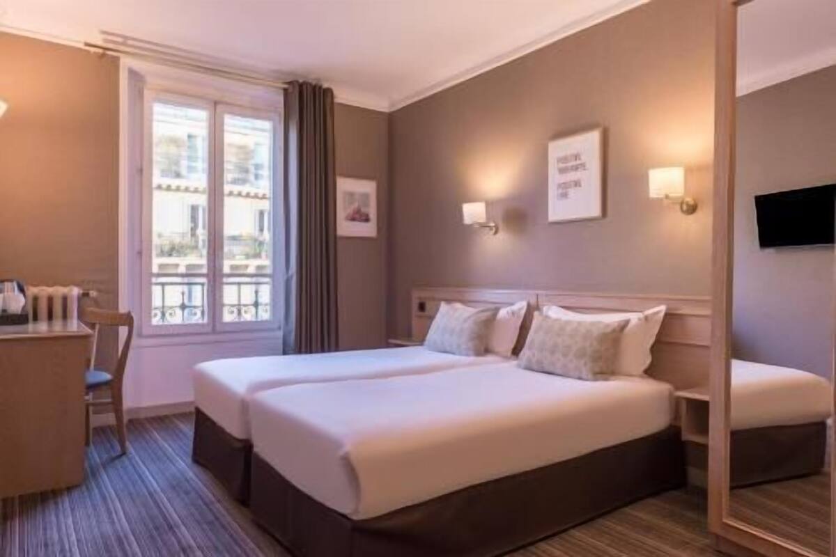 Une chambre d’hôtel avec un lit double, un bureau, une chaise et une fenêtre donnant sur un paysage agréable.