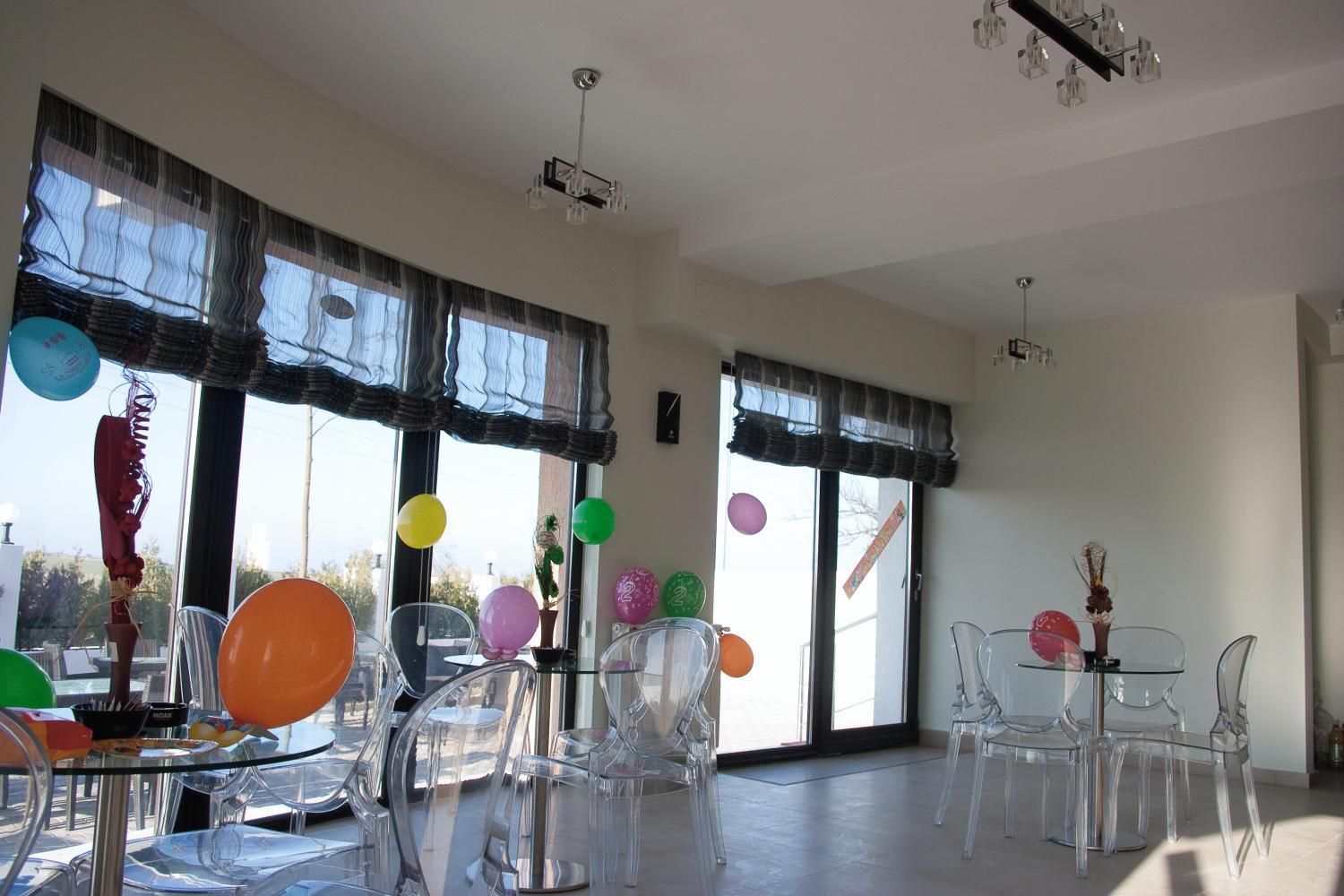 Une pièce spacieuse avec de grandes fenêtres, des chaises transparentes et une table en verre dressée pour un repas.