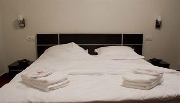 A neatly made bed with white linens and two folded towels on the side. - La Mer (Agigea)