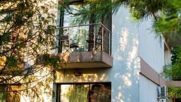 A multi-story building with balconies, outdoor seating, and a well-maintained lawn.