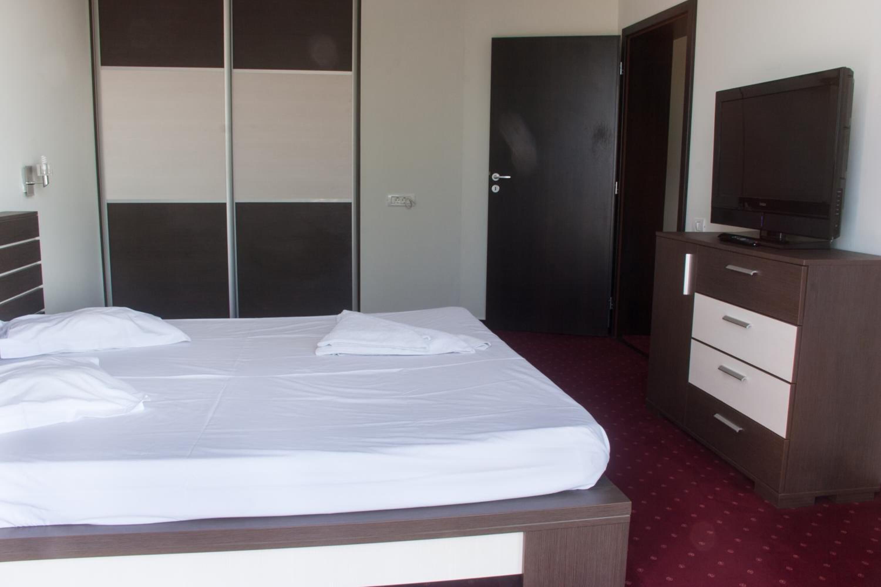 A hotel room with a bed, a wardrobe, a television, and a door.