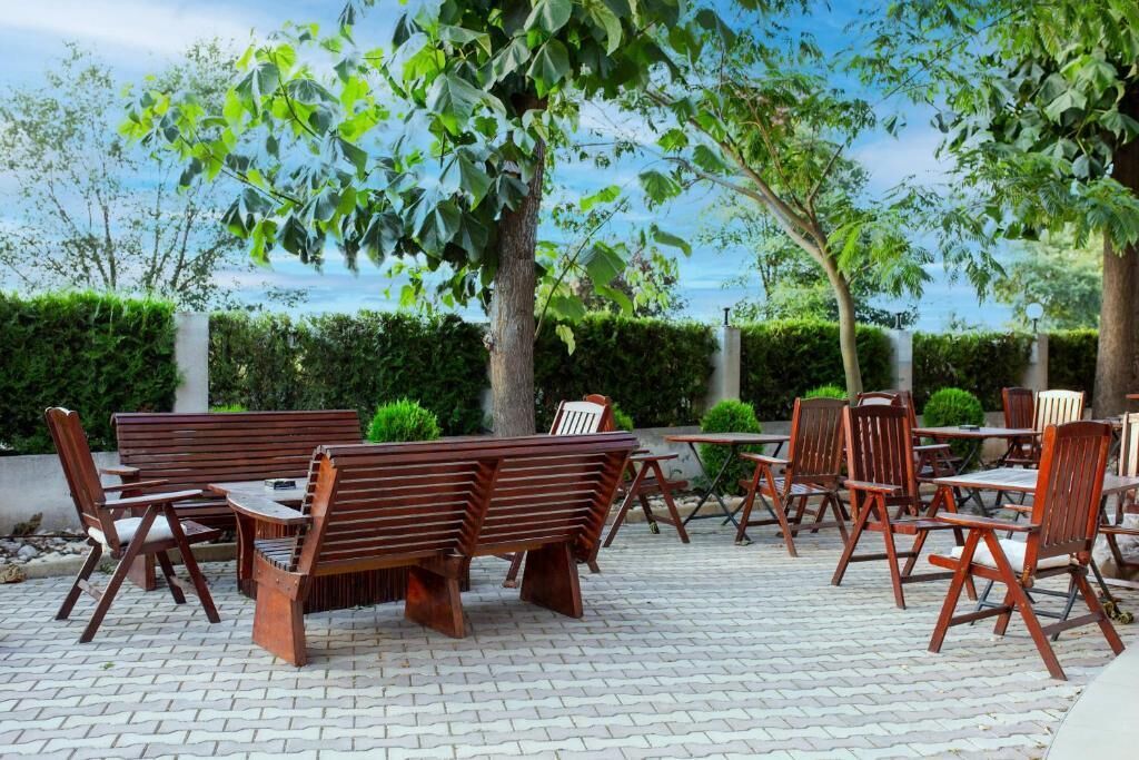 An outdoor seating area with wooden furniture and a hedge in the background.