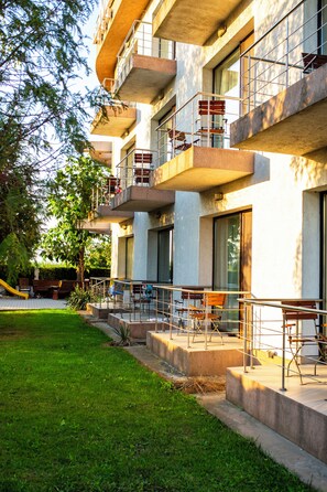 A multi-story building with outdoor seating areas, a grassy courtyard, and a playground.
