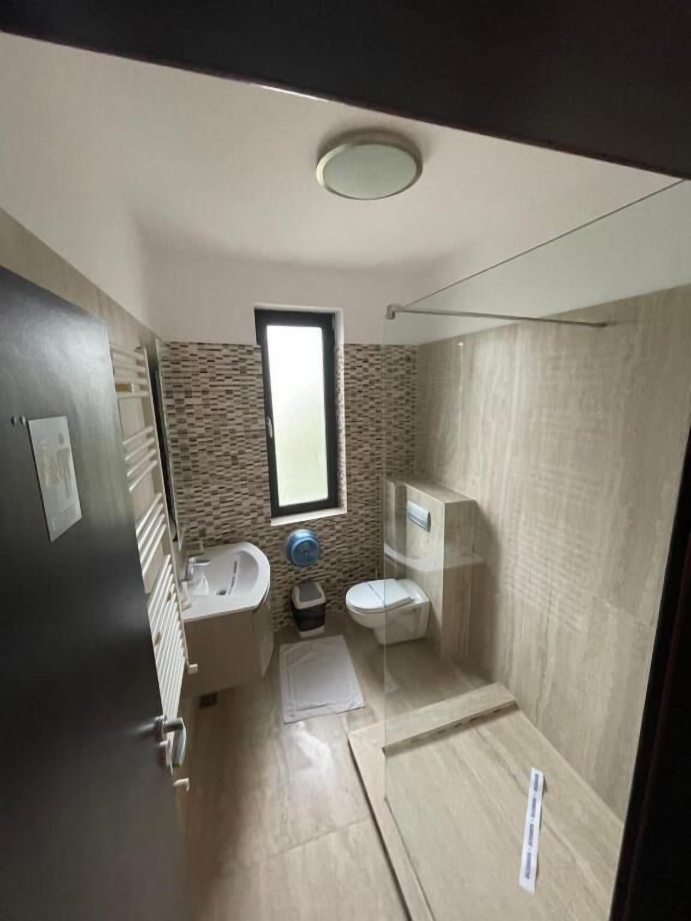 Een kleine badkamer met toilet, wastafel en douchehoek.