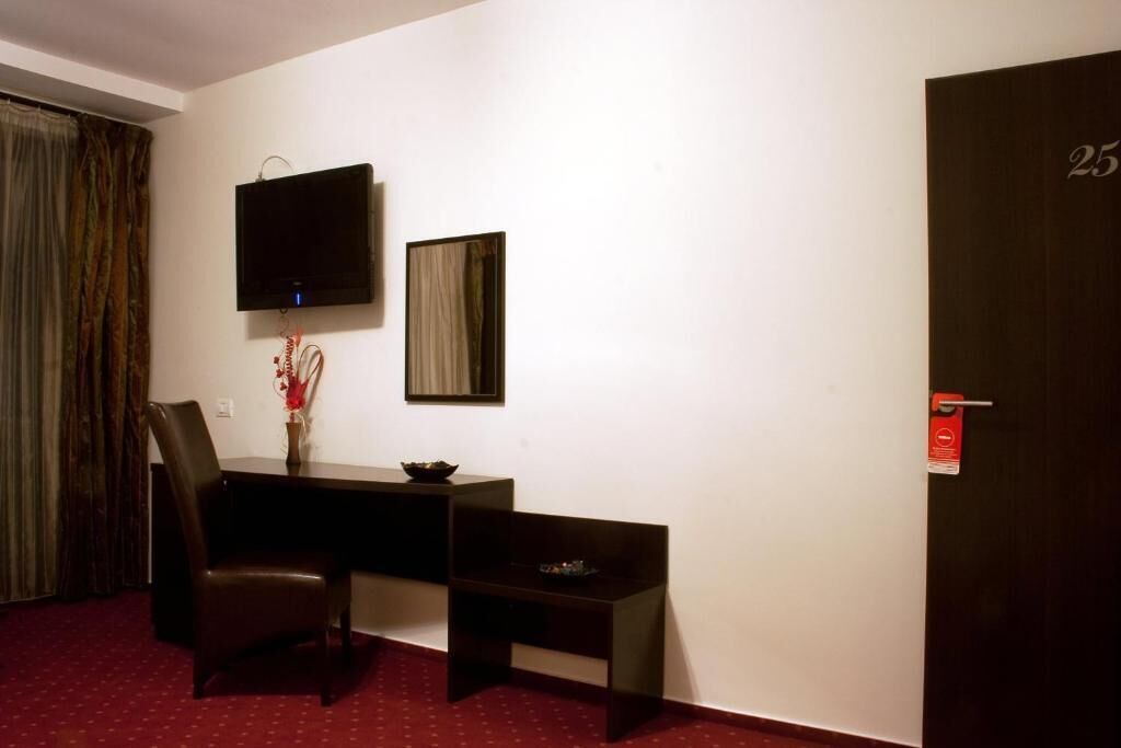 A hotel room with a desk, chair, TV, and a door marked with the number 25.