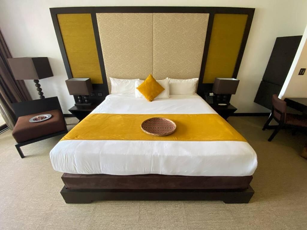 Une chambre d’hôtel avec un grand lit, deux tables de chevet, une chaise et une lampe.