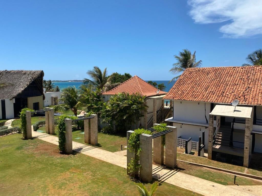 A coastal property with multiple buildings, a clear sky, and a view of the sea.