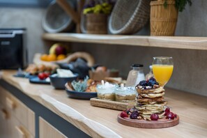 A breakfast buffet with various food items and a glass of orange juice. - Korali Palace (Naxos)