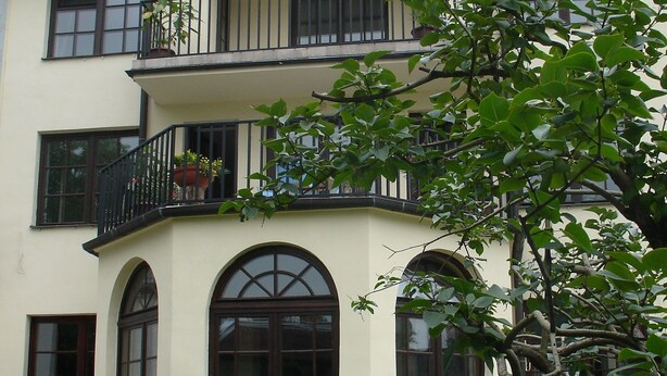 Un edificio de varios pisos con balcones, grandes ventanales de arco y una escalera que lleva a la entrada.