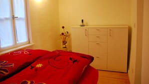 A bedroom with a bed, a wardrobe, a window, and a vase with flowers. - Ferienwohnung am Rathaus Bamberg (Bamberg)