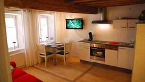 A compact kitchen with a dining area, a TV mounted on the wall, and a red chair in the foreground. - Ferienwohnung am Rathaus Bamberg (Bamberg)