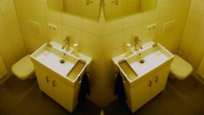 A mirrored view of a bathroom with two sinks, a toilet, and tiled walls. - Ferienwohnung am Rathaus Bamberg (Bamberg)