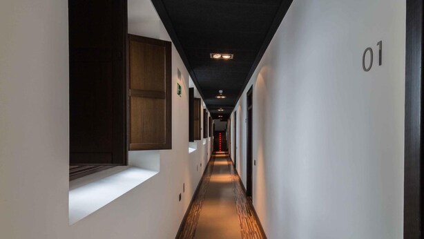 A hallway with a wooden floor, white walls, and a dark ceiling. - Hotel Villa de Setenil (Setenil de las Bodegas)